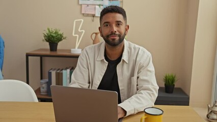 Wall Mural - African american man with beard works on laptop in modern home office setting, exemplifying remote work and lifestyle