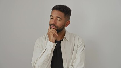 Poster - Young african american man, standing, wearing a shirt, thoughtfully pondering a serious question with hand on chin, over an isolated white background