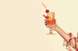 a vintage retro female hand holding a cocktail isolated on a plain background, 1960s and 70s style