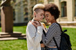 © Bliss - Two young women, lesbian couple, share a warm hug surrounded by nature in a peaceful park setting.