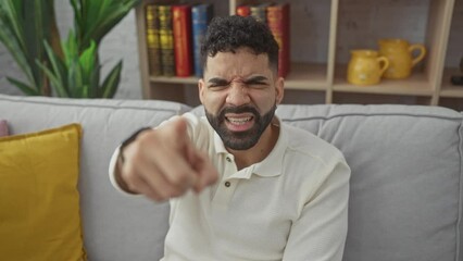 Canvas Print - Angry young hispanic man pointing fiercely at camera, displeased and furious, experiencing frustration at home