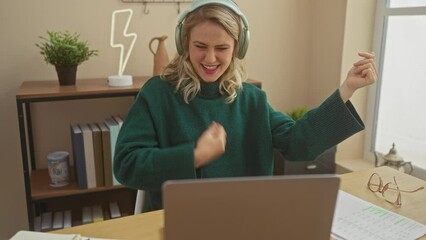 Canvas Print - Young woman enjoys music on headphones while working on laptop indoors