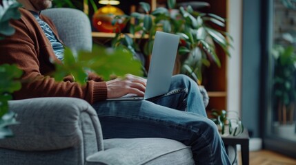 Aufkleber - A man sitting on a couch while using a laptop. Suitable for technology and remote work concepts