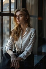 Poster - A woman sitting on a window sill looking out, suitable for various concepts and designs