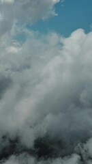Wall Mural - Flying through beautiful white fluffy clouds in blue sky. Airplane travel background. Vertical video