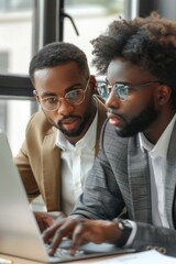 Poster - Two men sitting at a table working on a laptop. Suitable for business and technology concepts