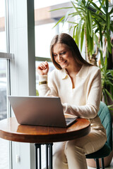 Poster - woman sitting at table using laptop computer