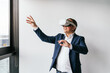 © Koldo_Studio - A businessman in a suit interacts with a VR headset, engaging with virtual reality technology in a modern office.