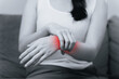© Suriyawut - Closeup of woman sitting on sofa holds her wrist, hand injury with red highlight