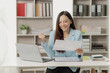 © MrAshi - Asian businesswoman working using a laptop computer Marketing report with calculator document on table Plan to analyze financial reports