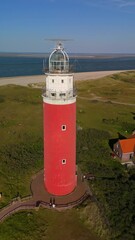 Wall Mural - Texel lighthouse on a summer day Netherlands Dutch Island Texel with sand dunes at the Wadden Island. drone aerial view from above during sunset at the beach with a sunset in the ocean