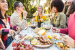 © Davide Angelini - Happy friends having bbq dinner party in garden restaurant - Multiracial young people eating grill meat and drinking red wine in backyard - Food life style concept with guys and girls sitting outdoors