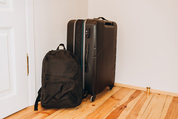 Black travel suitcase and backpack on the floor. Travel concept.