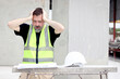 © Stella - Panic attacks senior worker engineer foreman with safety vest and helmet put hands on head while staring at blueprint at construction site. Stressed elderly architect works at building site workplace.