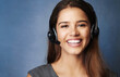 © peopleimages.com - Businesswoman, portrait and studio with headset, smile and communication for goals. Agent, call center operator or reporter for content creation, publishing or press startup on blue background