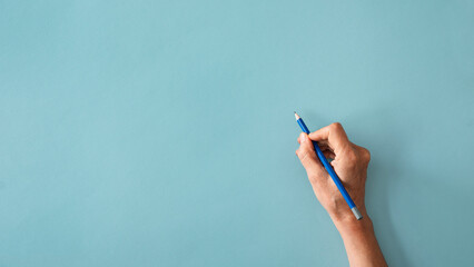 Wall Mural - Woman hand are writing on blue background