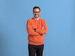 © Moon Safari - Portrait of male entrepreneur with arms crossed smiling and posing confidently over blue background