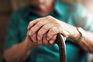 Senior man, hands and support with cane for old age, osteoporosis or care in retirement home. Closeup of elderly, pensioner or male person with a disability or walking stick for stability at house