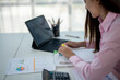 © Wasana - A woman is sitting at a desk with a laptop and a notebook