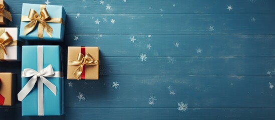 Poster - View of Christmas gift boxes on a blue wooden background providing room for your personalized greetings Perfect for a top down flat lay copy space image