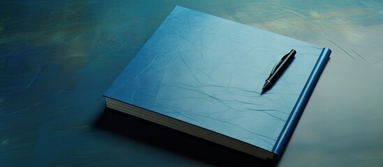 A copy space image showing a pen placed on a blue notepad which is sitting on a table