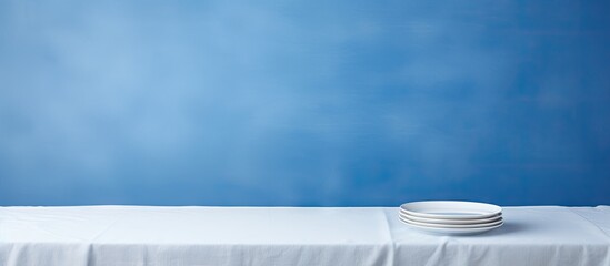 Poster - Copy space image of a white wooden table with a new blue tablecloth featuring an empty plate on top