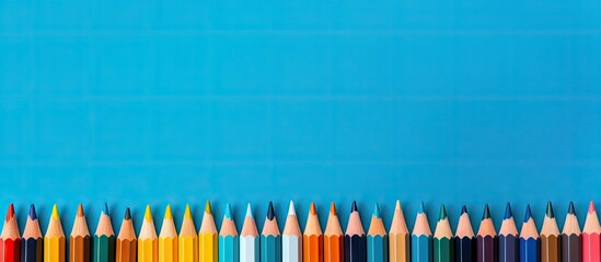 Poster - A copy space image for art school or back to school featuring color pencils laid out on a blue background