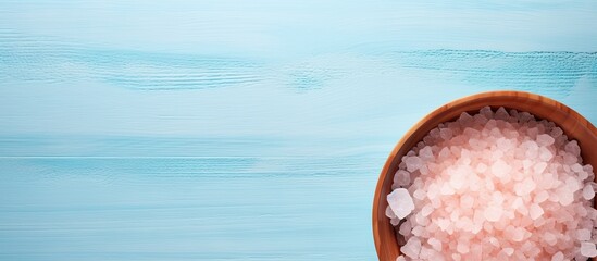 Poster - Top down flat lay image of a pink Himalayan salt plate on a pastel blue background with ample space for copy