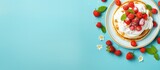 A top view of a plate with pancakes topped with whipped cream strawberries mint and sweet cherries on a bright blue background Ample copy space available