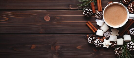 Poster - Brown ceramic mug of traditional hot drink with marshmallow and star anise in Christmas atmosphere with Christmas branches and cones on wooden background Close up top view copy space