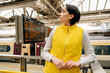 © Iryna - worried Woman looking departure board waiting for train at  train station. Travel lifestyle concept.