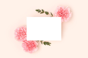 Wall Mural - empty paper card mockup, pink carnation flowers and green eucalyptus branches on a beige background.