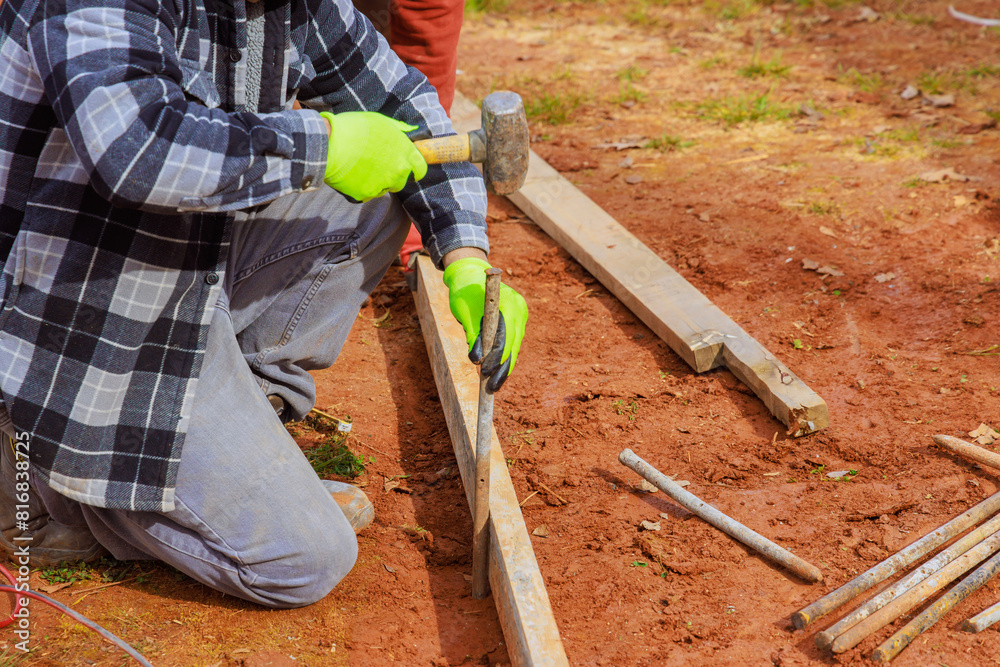 Construction workers produce templates with removable timber formwork for pouring concrete on foundations