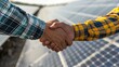 © At My Hat - Two people shaking hands in front of a solar panel. Concept of cooperation and partnership between the two individuals