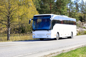 Wall Mural - white coach bus transports passengers on road through rural scenery on a day of spring.