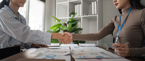 Wall Mural - Asian women shaking hands in a modern office. Concept of business agreement, partnership, and success