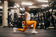 © Dusan Petkovic - Side view of a strong african american sportswoman doing lunges with dumbbells at gym.