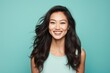 © Markus Schröder - Portrait of a smiling asian woman in her 20s smiling at the camera on soft teal background