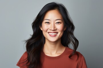 Canvas Print - Portrait of a grinning asian woman in her 30s smiling at the camera isolated on soft gray background