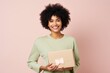 © Markus Schröder - Portrait of a content afro-american woman in her 30s holding a box while standing against pastel or soft colors background
