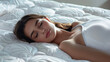© OMD - A young woman peacefully sleeping on a white, patterned mattress in a well-lit room, wearing a white tank top. The scene emanates calmness and relaxation.