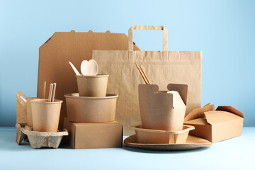 Sticker - Eco friendly food packaging. Paper containers, tableware and bag on white table against light blue background