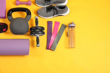 Different sports equipment on yellow background, flat lay. Space for text