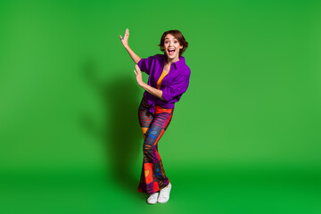 Poster - Photo portrait of funny young woman in purple stylish shirt trendy vintage pants and brown bob haircut dancing isolated on green color background