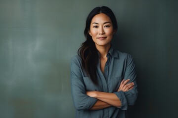 Wall Mural - Portrait of a tender asian woman in her 40s with arms crossed on minimalist or empty room background