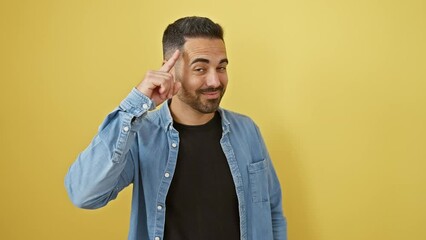 Sticker - Cheerful young hispanic guy wearing denim shirt, pointing finger at head, smiling with great idea concept, fond memory isolated on yellow background