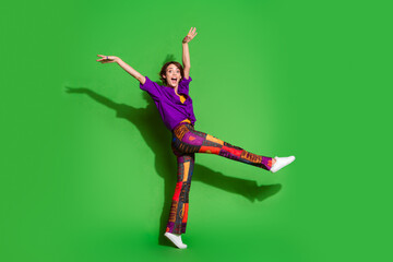 Poster - Photo of young funky model positive girl wearing hipster outfit raised arms up big giant step joking for isolated on green color background