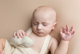 Fototapeta Do akwarium - a small child with a toy lies on a light background. newborn boy. baby's first photo shoot