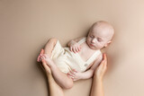 Fototapeta Do akwarium - a small child lies on a light background. newborn boy in mother's hands. baby's first photo shoot