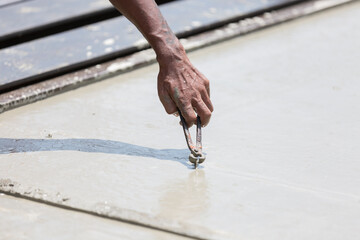 Hands of construction worker working and inspecting with wet concrete at precast concrete wall construction site. Worker or mason working or making smooth surface of concrete at site work